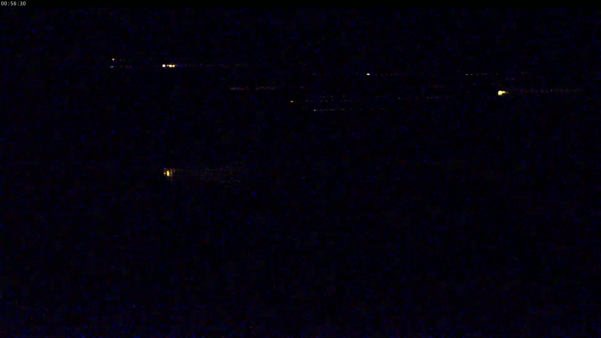 A nighttime long shot shows a dark landscape with a few small, distant lights.