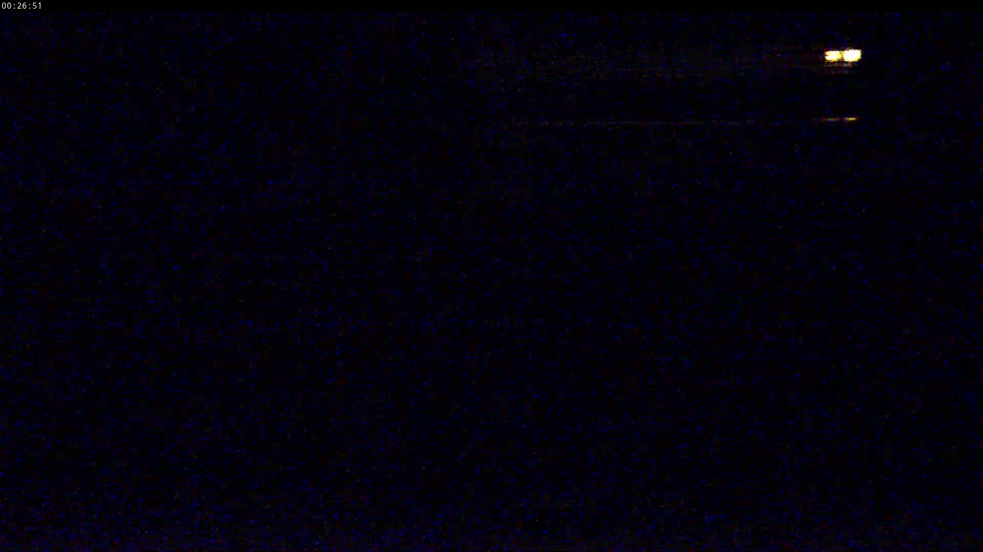 A nighttime, dark scene with two small, bright lights visible in the distance.