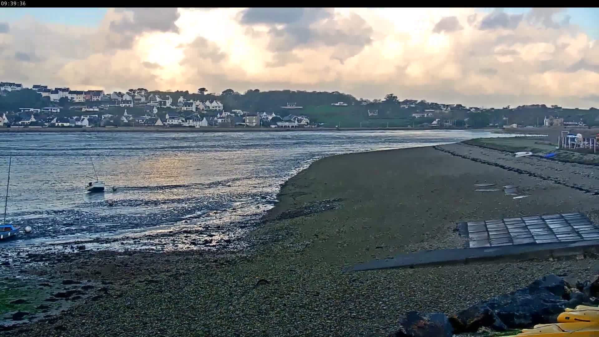 A nighttime, low-light view shows a dark body of water reflecting faint lights from the shore and a few distant lights on land.