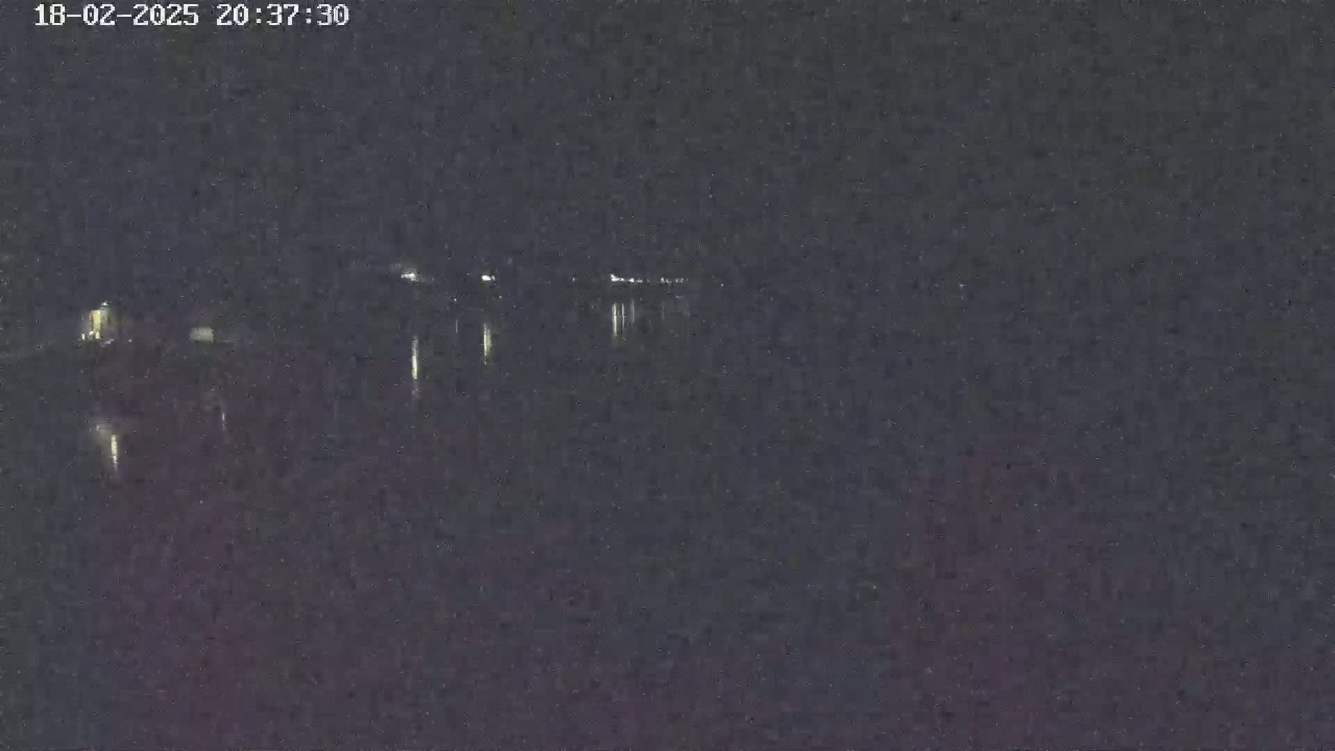 A nighttime, low-light view of a body of water reflecting a few distant lights.