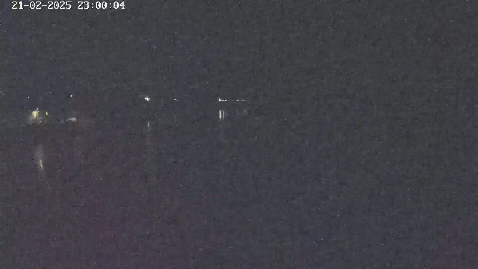 A nighttime, low-light view shows a dark body of water with faint lights in the distance.