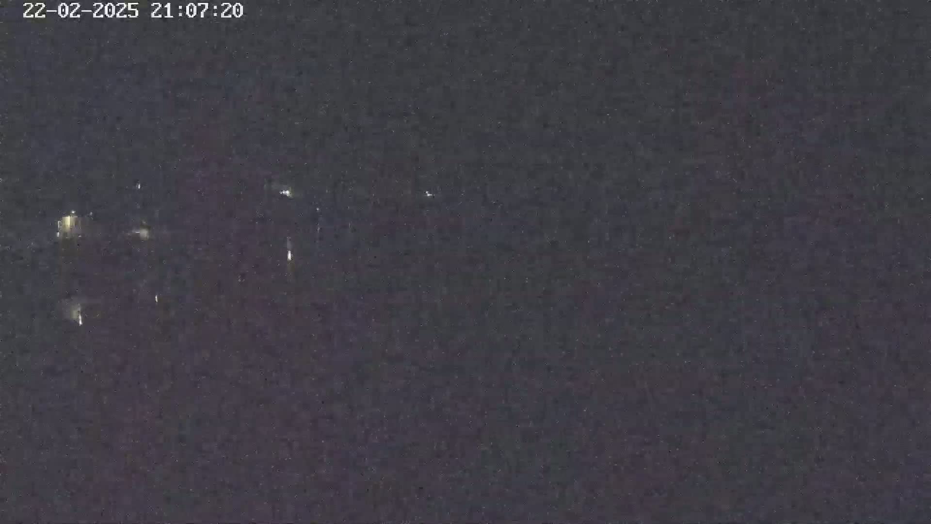 A nighttime, low-light view shows faint, distant lights possibly from a city or town.