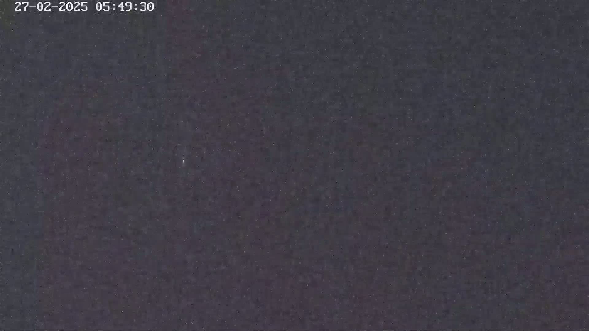 The image shows a dark, grainy, and mostly featureless surface.