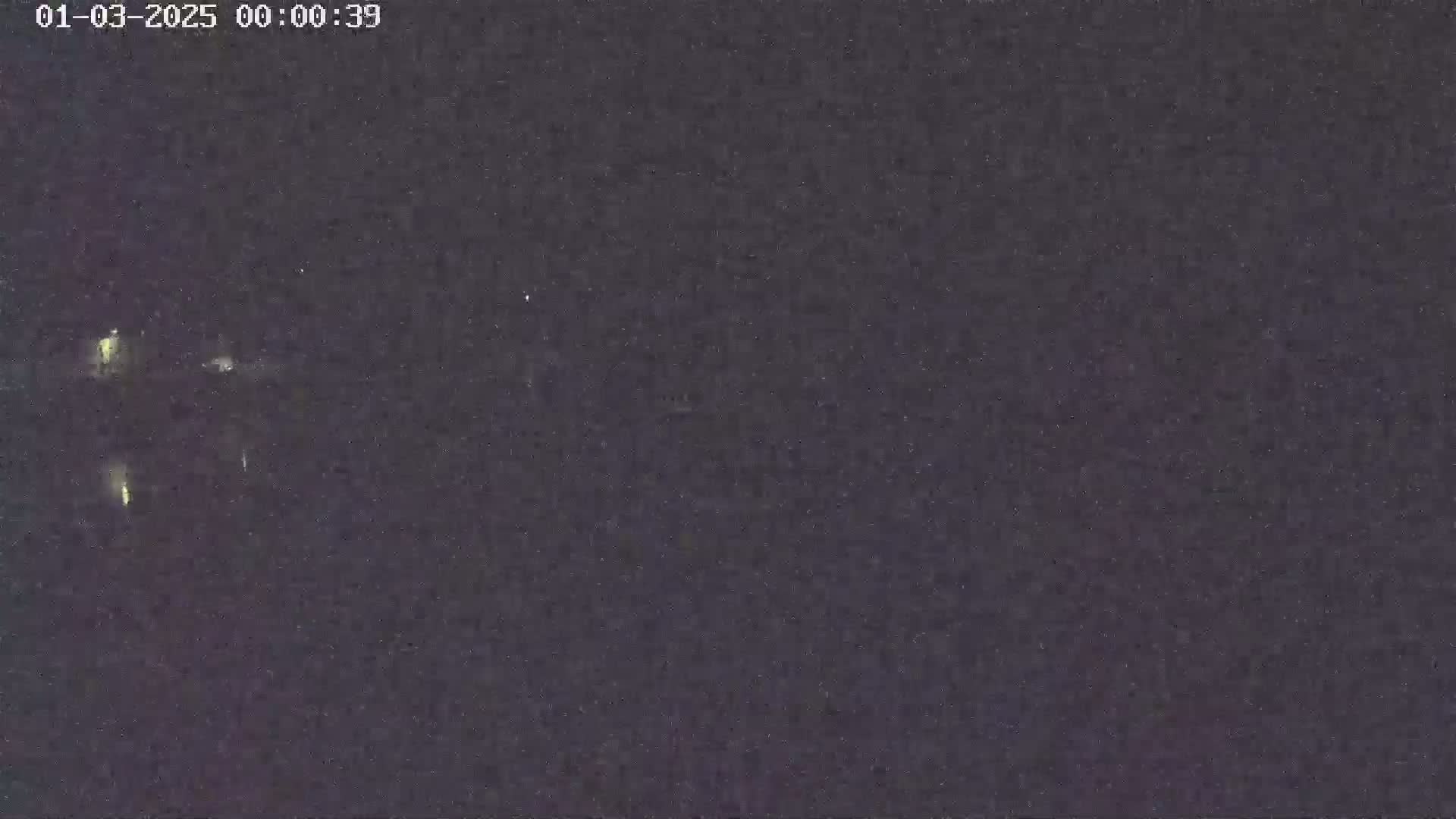 A nighttime, low-light view shows several faint, distant lights in a dark, possibly overcast sky.