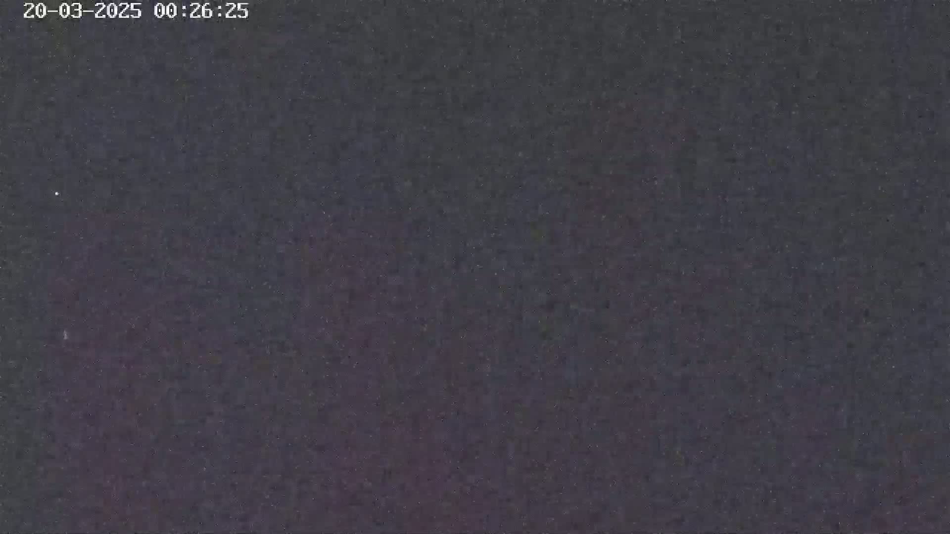 A dark, grainy image shows a night sky with a few faint stars visible.