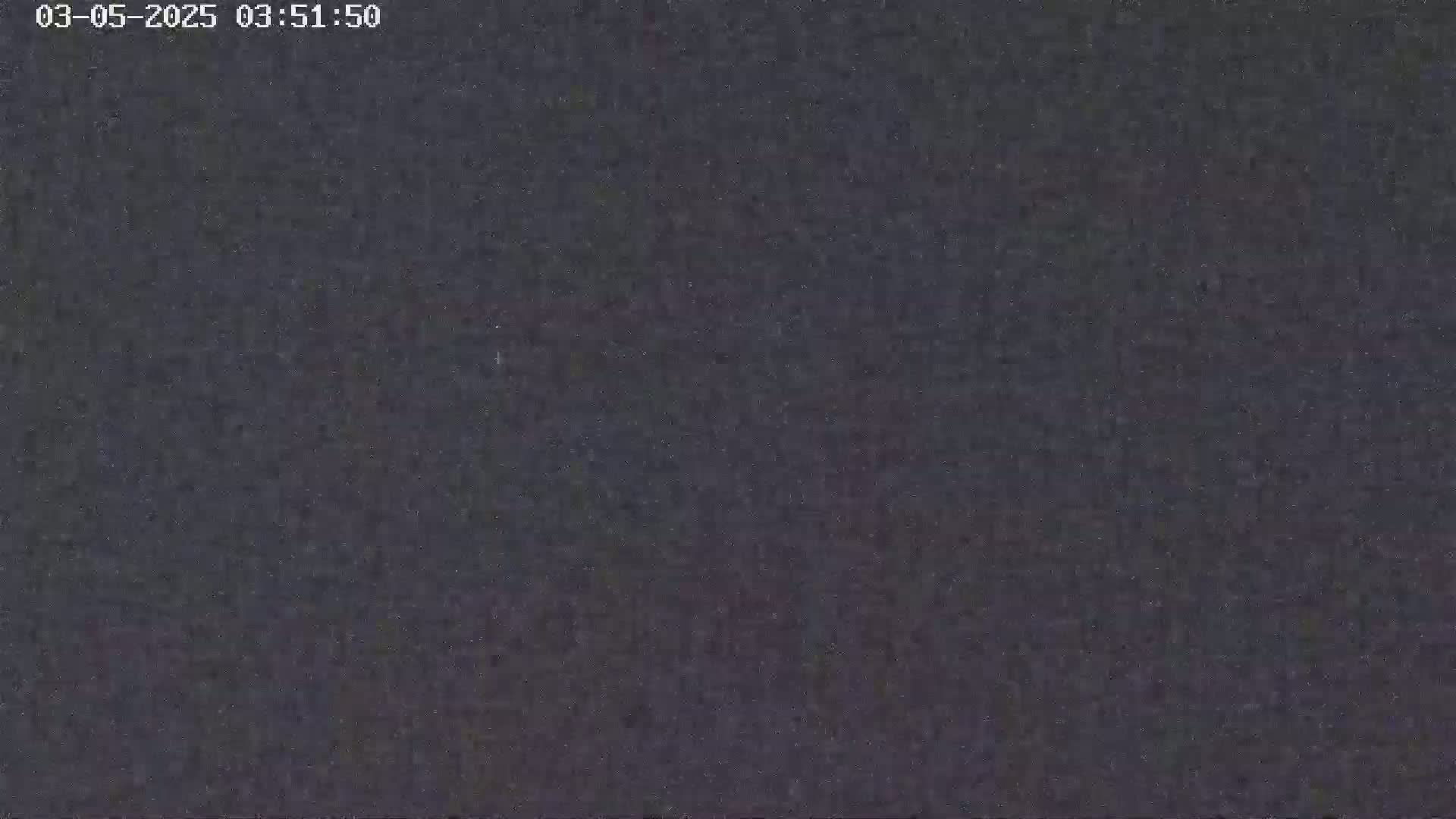 A dark, grainy image shows a night scene with an overcast sky.