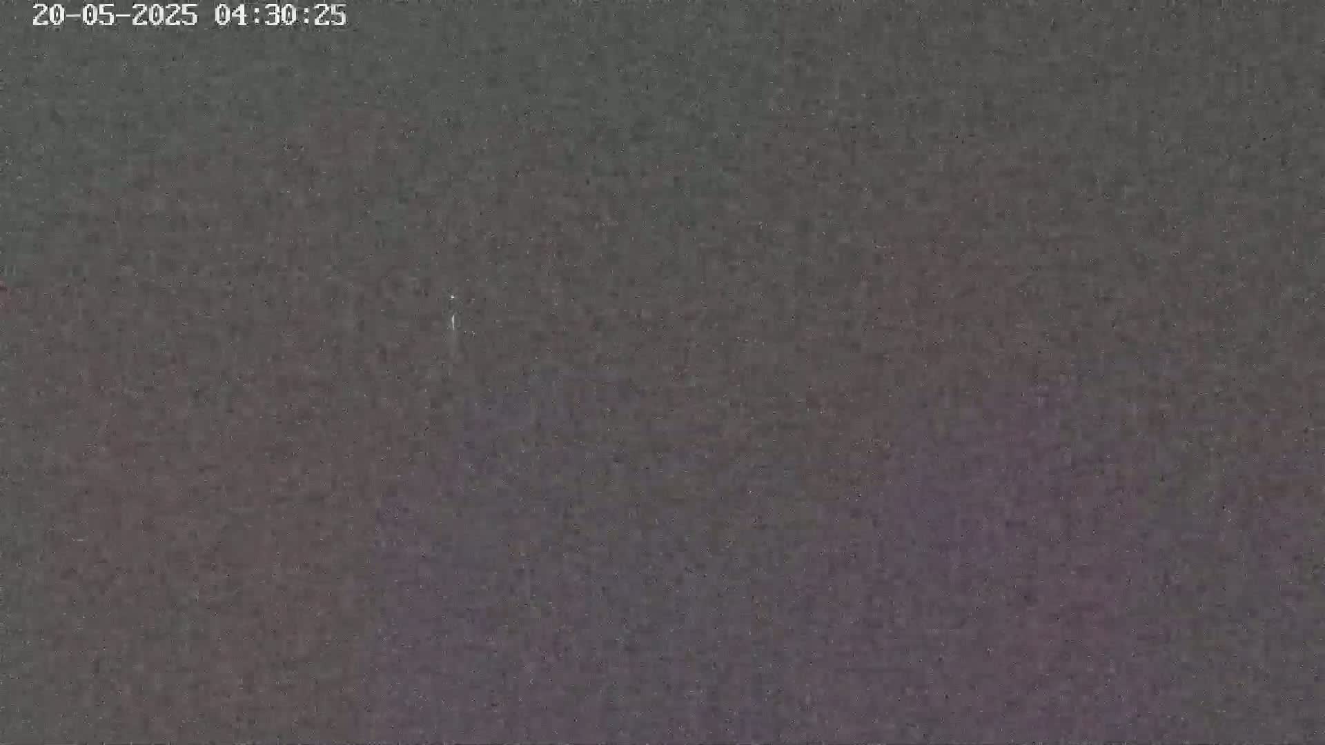 A dark, grainy image shows a mostly uniform, dark gray-purple sky at night.