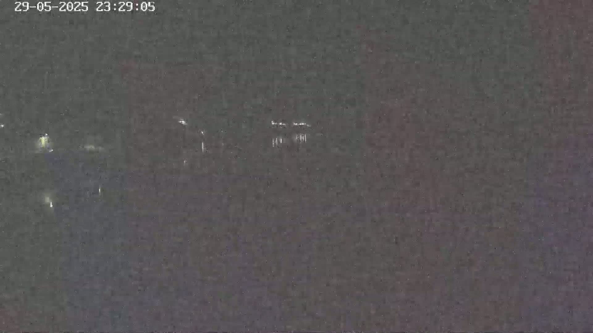 A nighttime long shot shows faint lights in the distance under a dark sky.