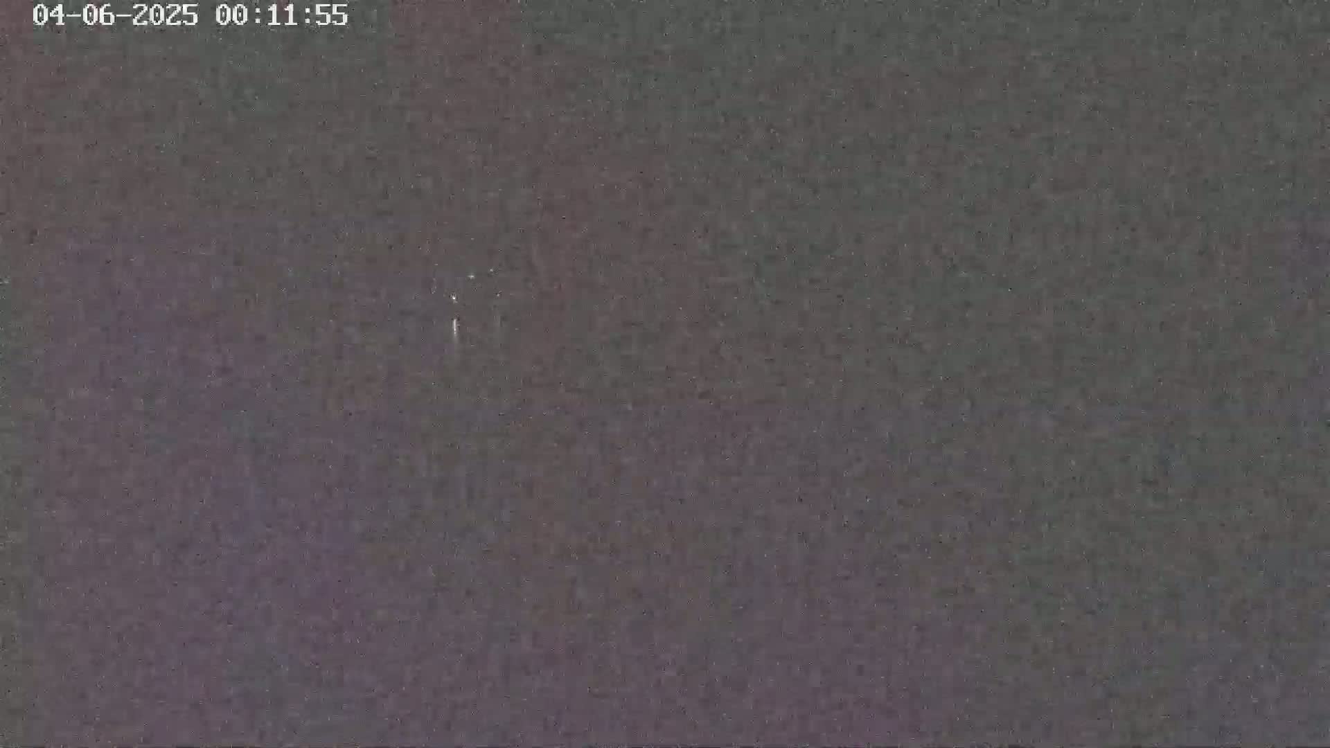 A dark, grainy image shows a night sky with very faint light sources.
