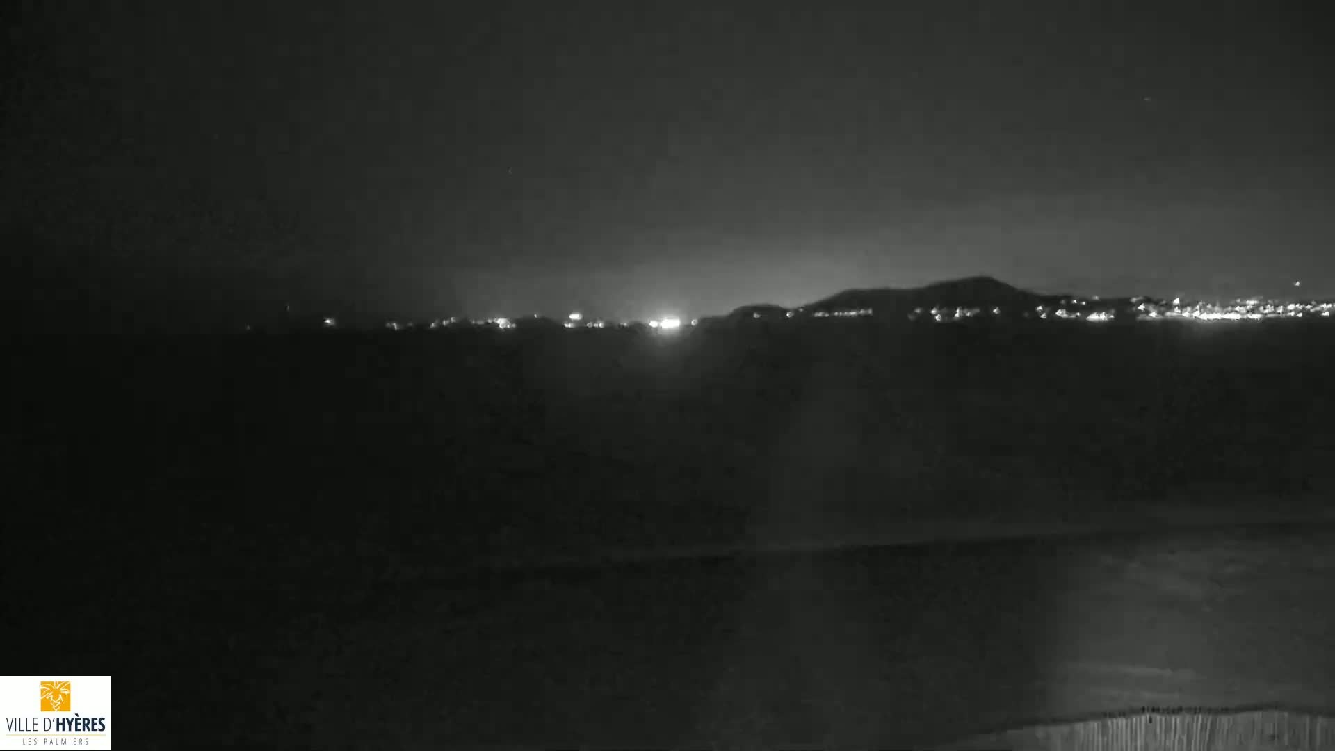 A nighttime, low-light view shows a distant cityscape illuminated against a dark sky.