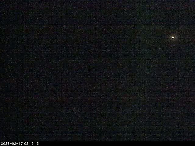 A single bright light is visible in a dark, nighttime sky.