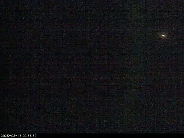 A single, bright light is visible in a dark, nighttime sky.