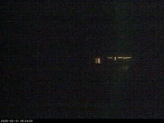 A dark, nighttime scene shows a few faint lights in the distance.