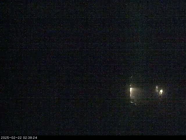 A dark, nighttime scene shows faint lights in the distance.