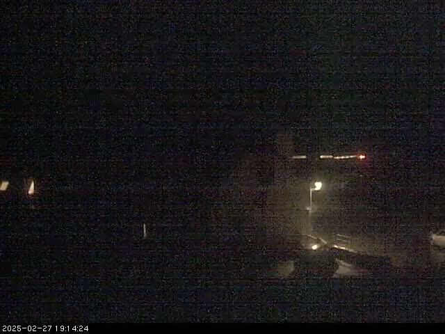 A nighttime, low-light view of a dimly lit road with a single lamppost visible in the distance.