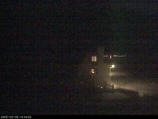 A dimly lit building is visible at night in snowy conditions.
