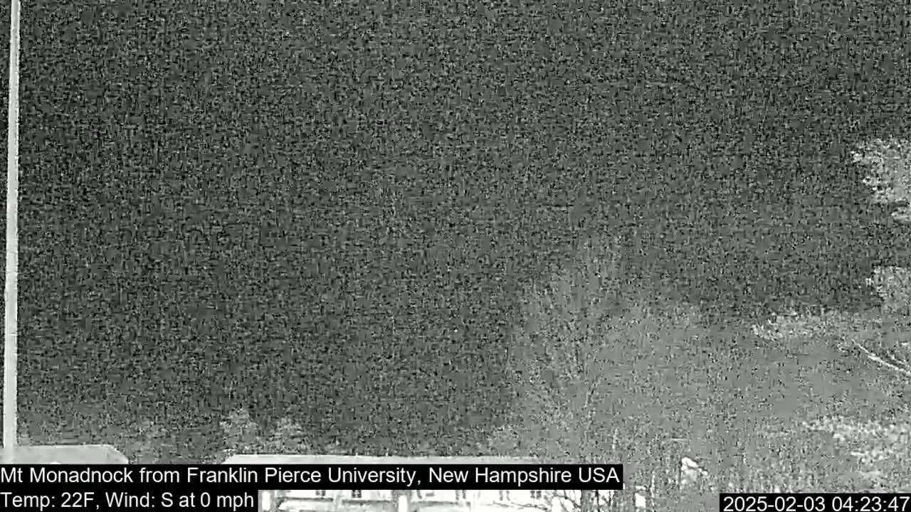 A nighttime, low-light view of a dark landscape with a calm wind and a temperature of 22 degrees Fahrenheit.