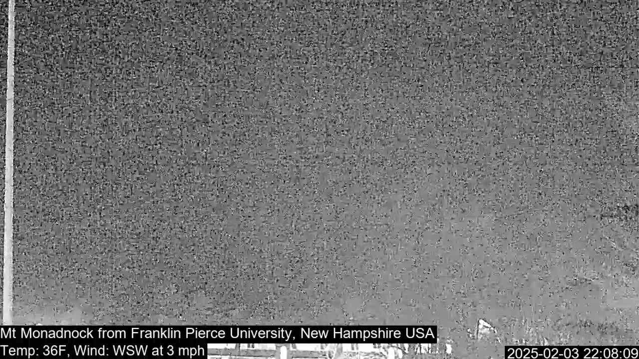 A nighttime, low-resolution image shows a mostly obscured view of a distant mountain under a dark sky with a 3 mph wind from the west-southwest and a temperature of 36°F.