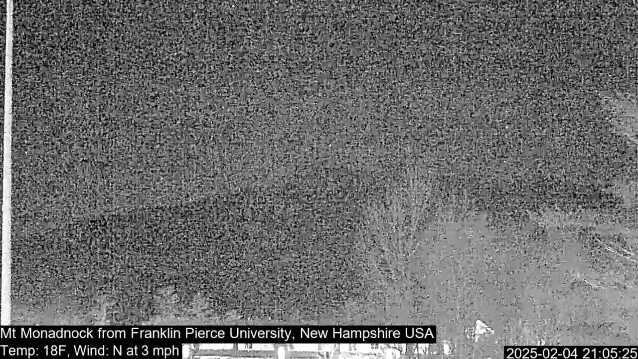 A nighttime, low-resolution image shows a dark, blurry view of a landscape with a temperature of 18°F and a 3 mph north wind.