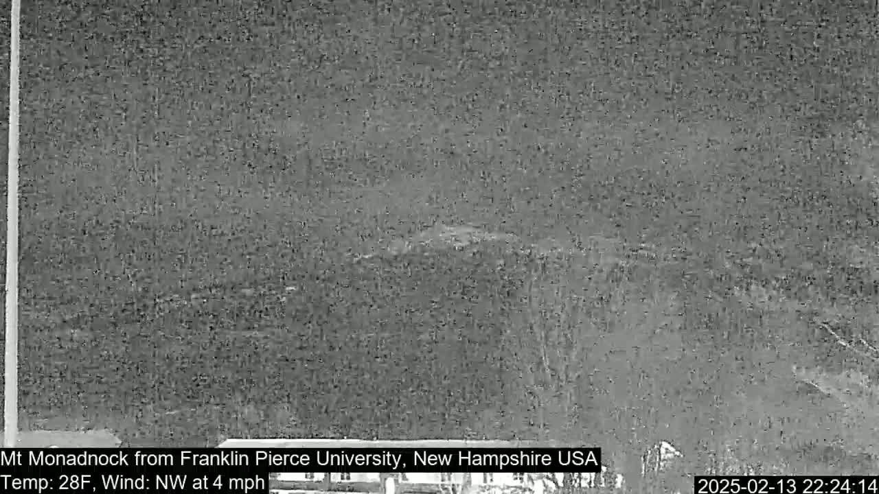 A nighttime, low-light view of a distant, snow-covered mountain under a dark sky with a northwest wind at 4 mph and a temperature of 28°F.
