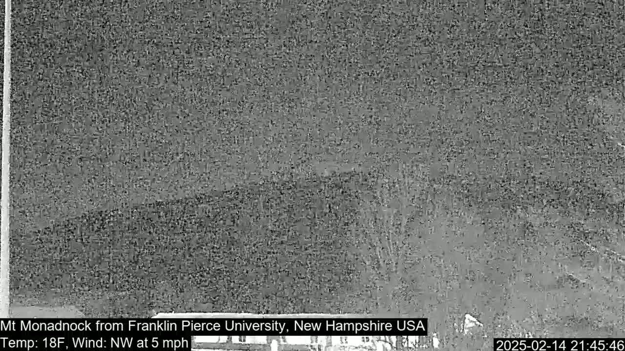 A nighttime, low-visibility view of a distant mountain under a cloudy sky with a northwest wind at 5 mph and a temperature of 18°F.