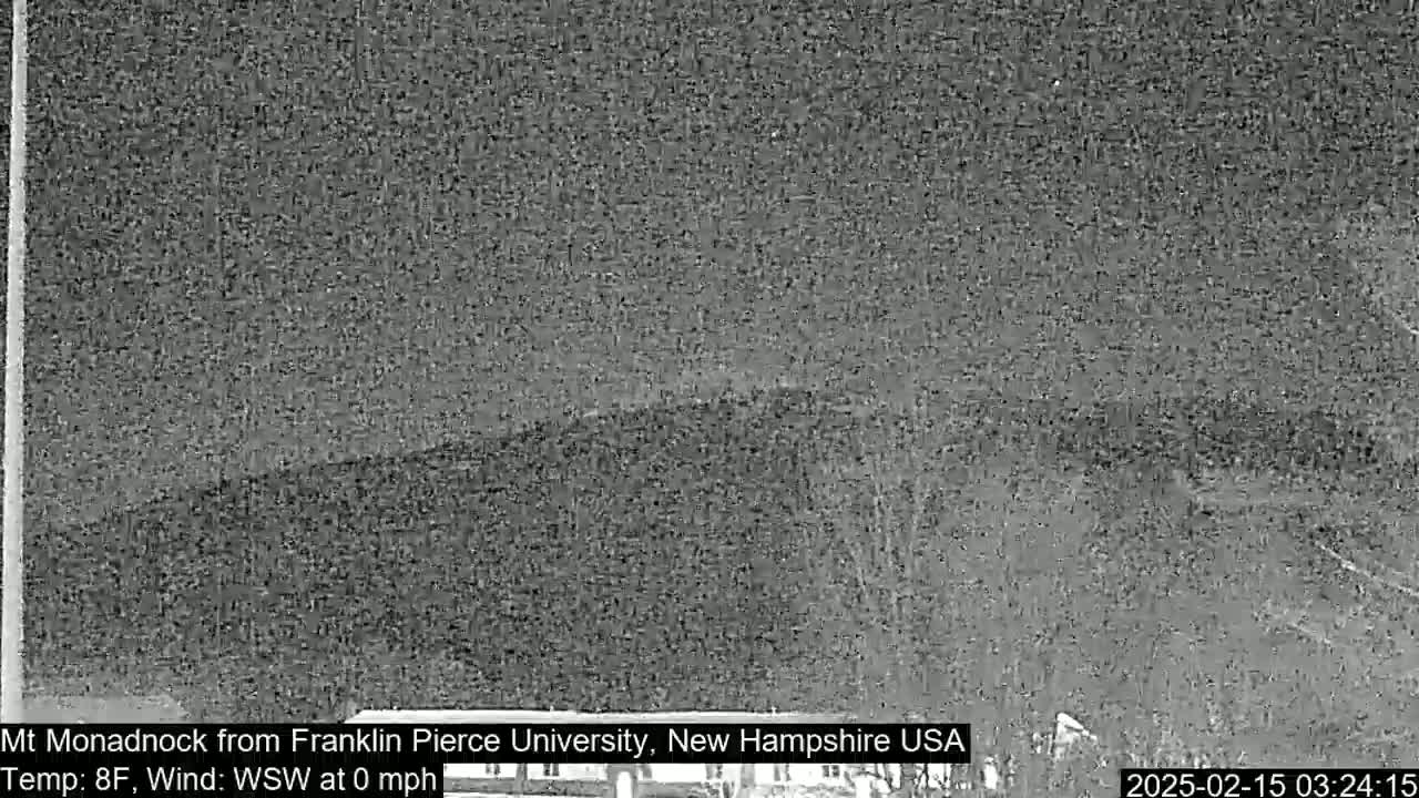 A nighttime, low-resolution image shows a dark, distant mountain range under a clear, dark sky.