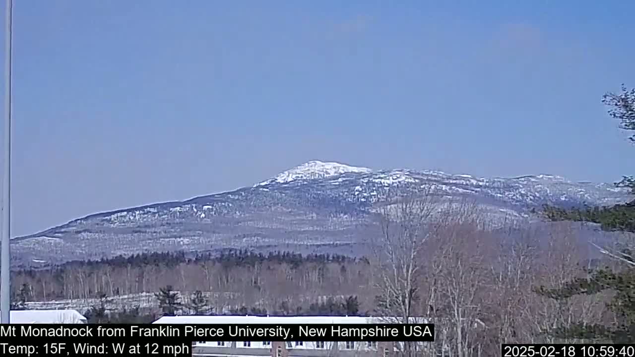 A snow-capped mountain range is visible in the distance under a clear blue sky, with a 15°F temperature and a 12 mph west wind.