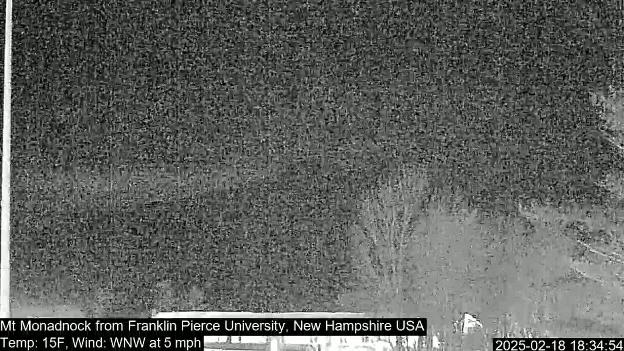 A nighttime, low-resolution view of a dark, snowy landscape with a 15°F temperature and a west-northwest wind at 5 mph.