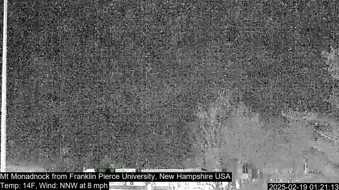A blurry, nighttime image shows a snow-covered landscape with a northwest wind at eight miles per hour and a temperature of fourteen degrees Fahrenheit.