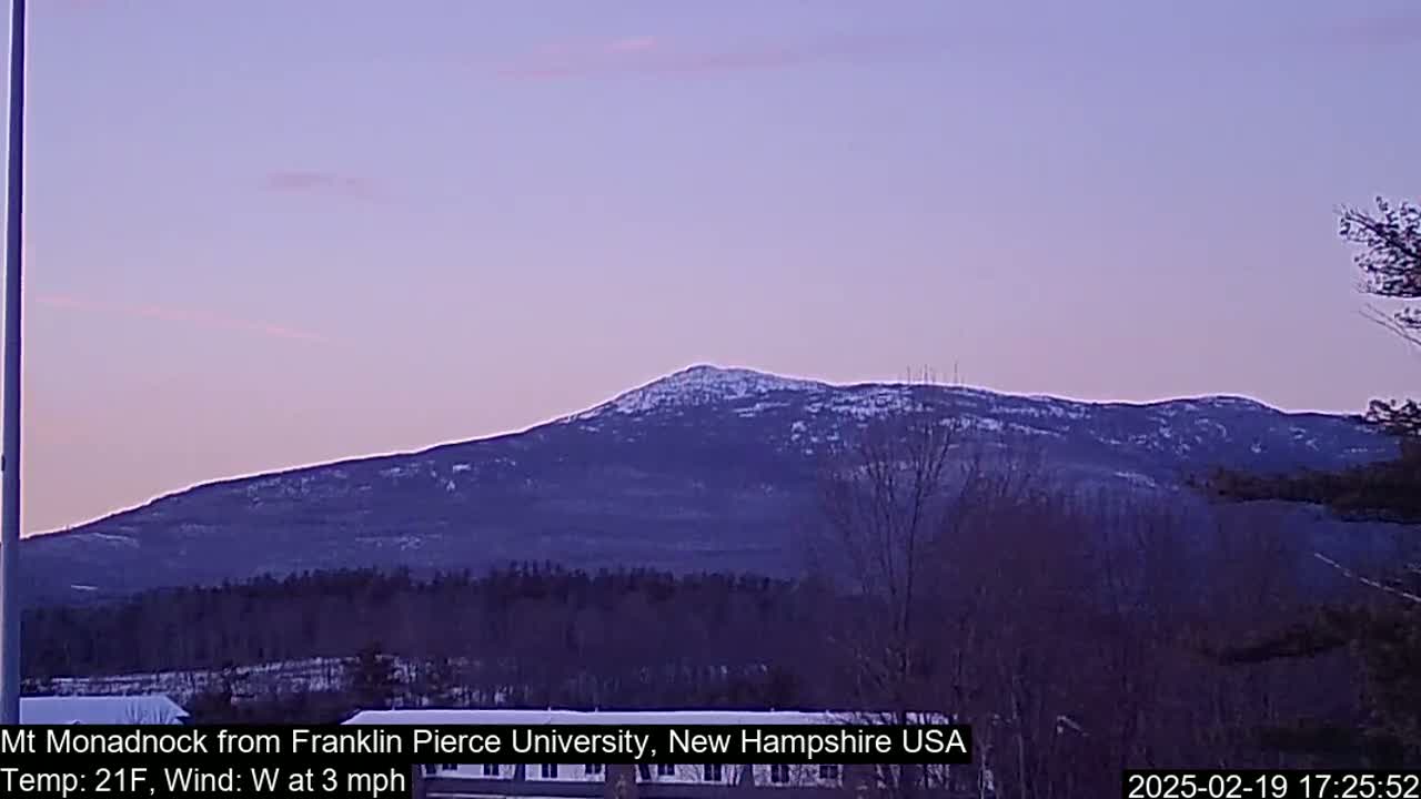 A snow-dusted mountain is visible under a pale purple twilight sky with a light westerly wind.