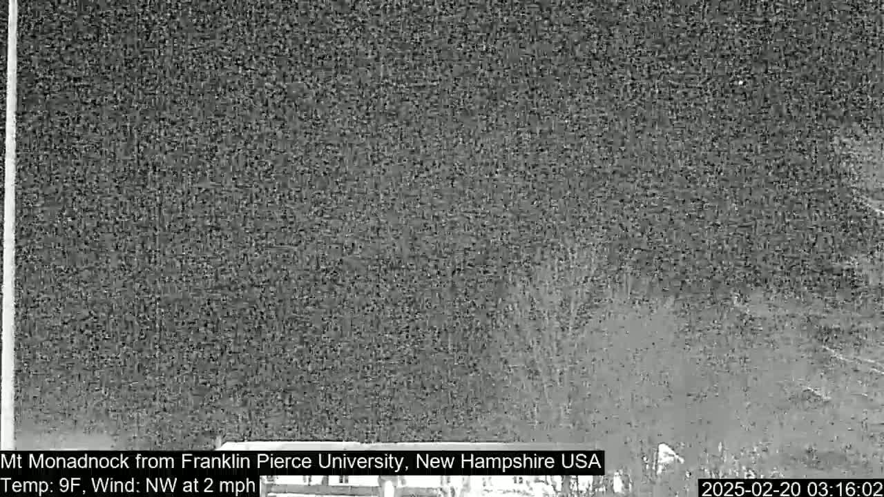 A nighttime, low-light view of a dark, snow-covered landscape with a northwest wind.