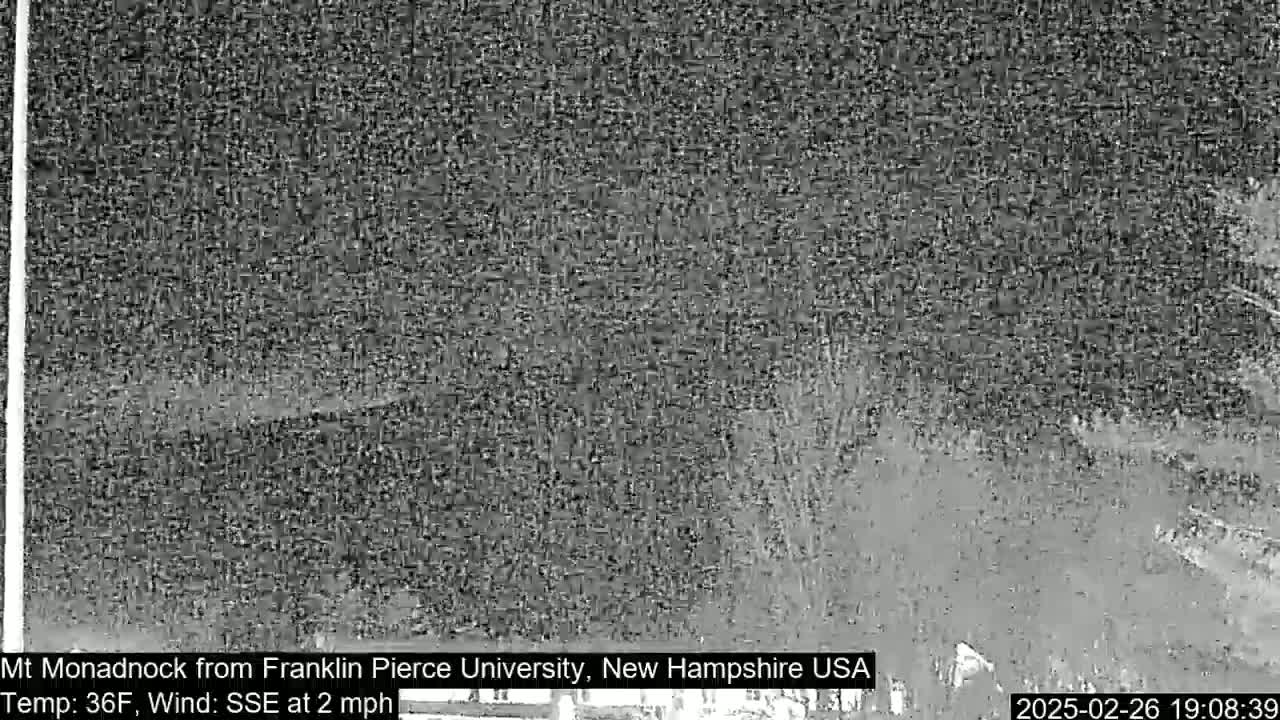 A grainy, nighttime image shows a dark, indistinct landscape under a dark sky.