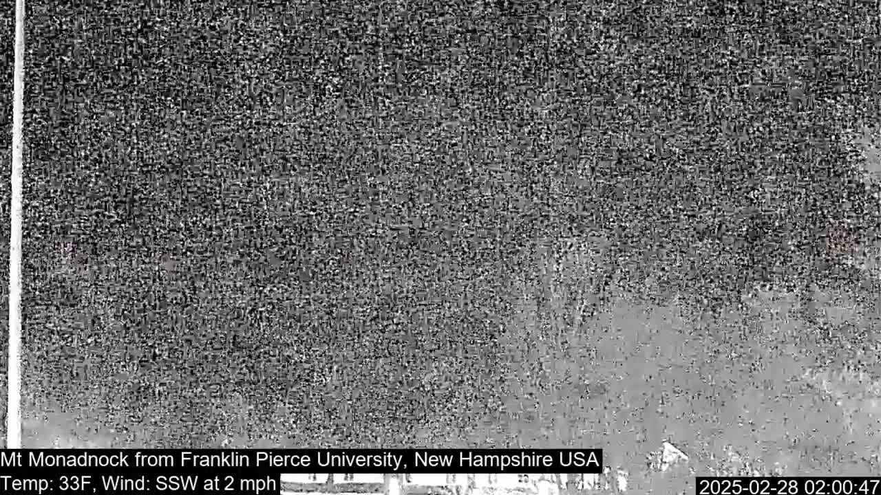 A grainy, low-light image shows a dark, indistinct view of a landscape under nighttime conditions.