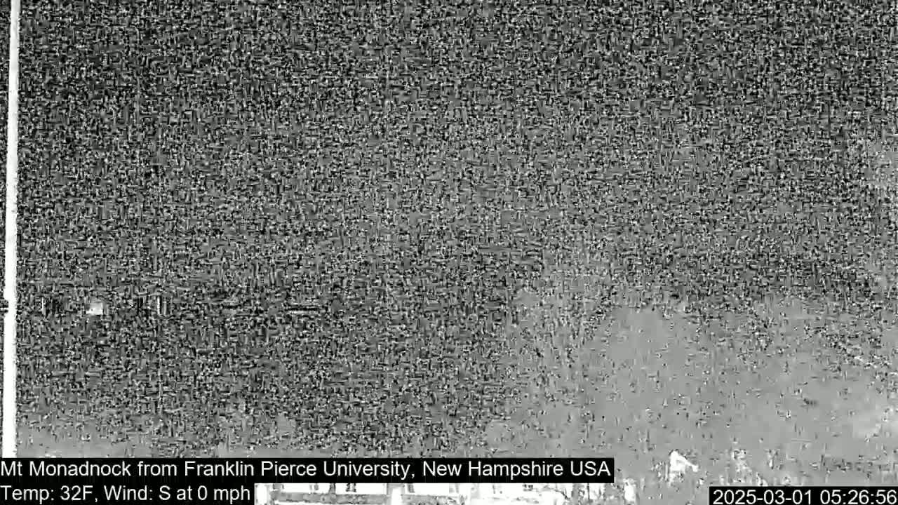 A blurry, grayscale image shows a distant, indistinct mountain range under a dark, possibly nighttime sky.