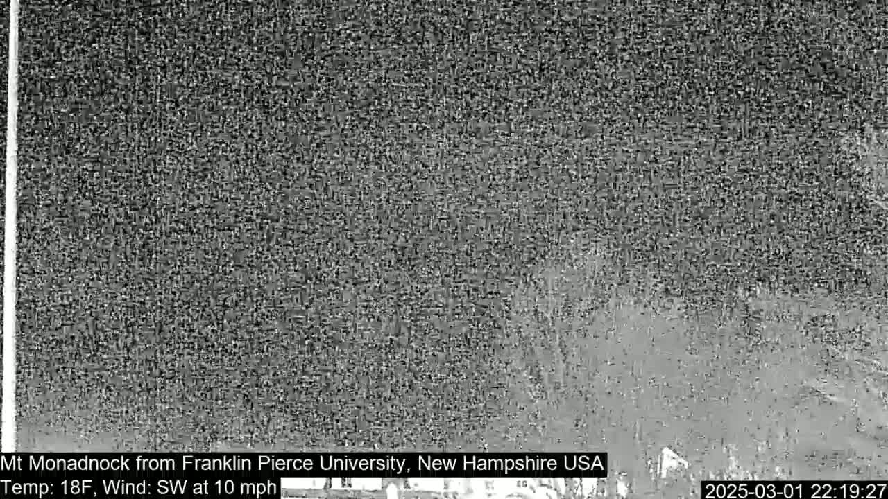 A grainy, low-light image shows a dark, indistinct landscape under nighttime conditions.