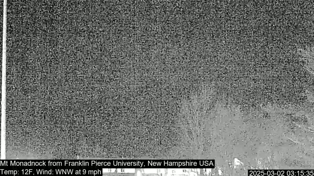 A grainy, low-resolution image shows a nighttime view of a snowy or hazy landscape under a dark sky.