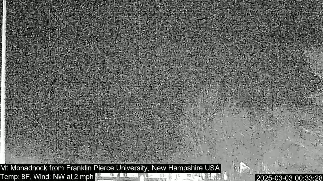 A grainy, low-light image shows a dark, indistinct landscape under a night sky.