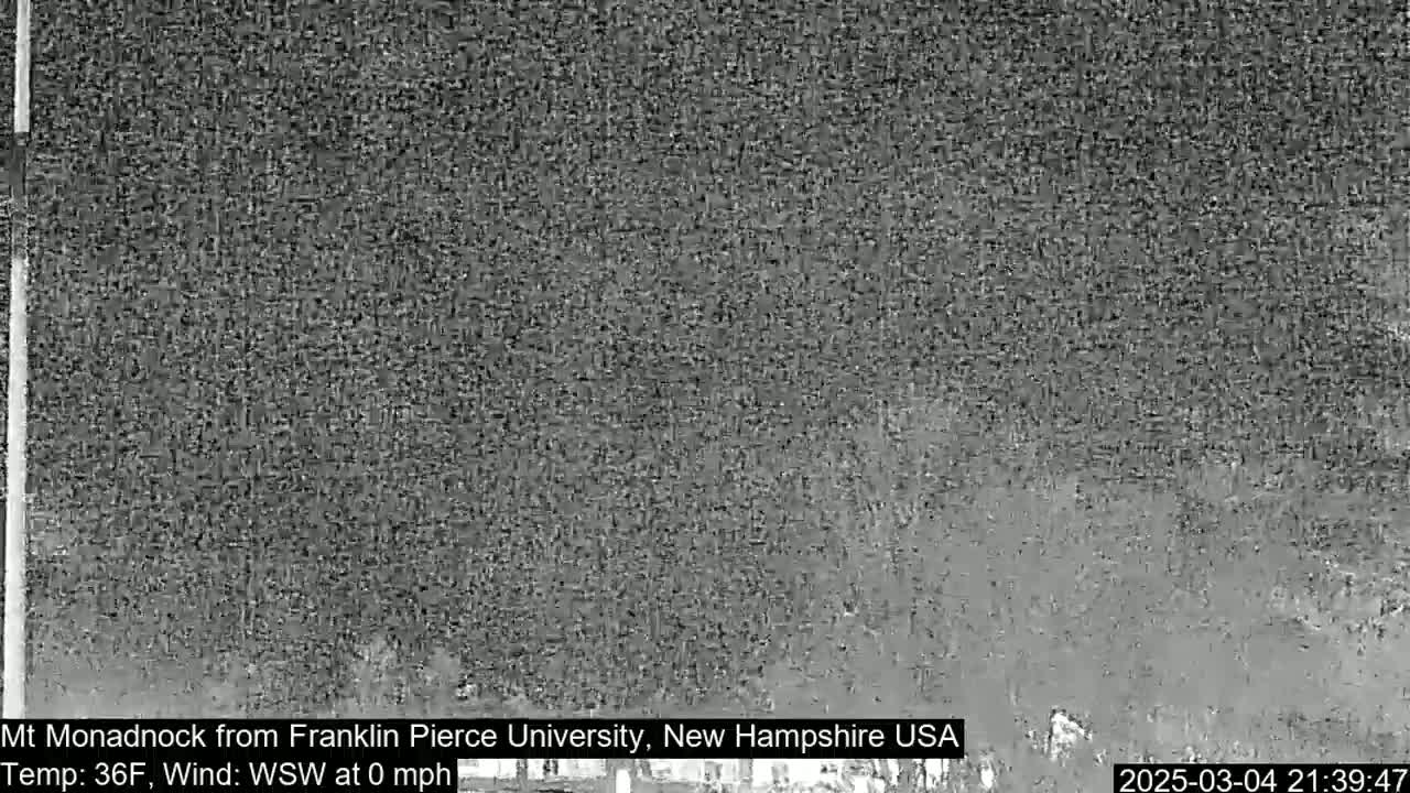 A grainy, low-light image shows a dark, indistinct landscape under calm conditions.