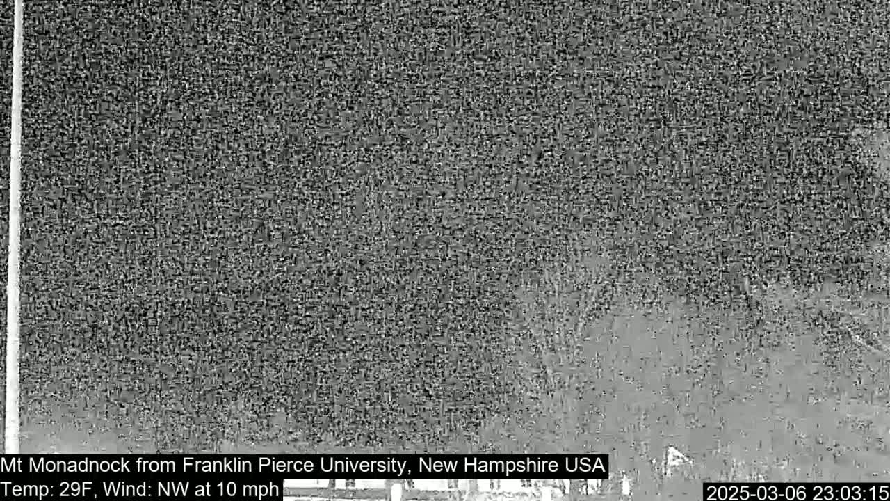 A blurry, grayscale image shows a distant mountain under a nighttime sky with a northwest wind at 10 mph and a temperature of 29°F.
