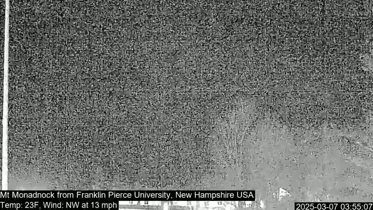 A grainy, low-light image shows a distant, indistinct view of a mountain, under a dark, possibly nighttime sky with a northwest wind at 13 mph and a temperature of 23°F.