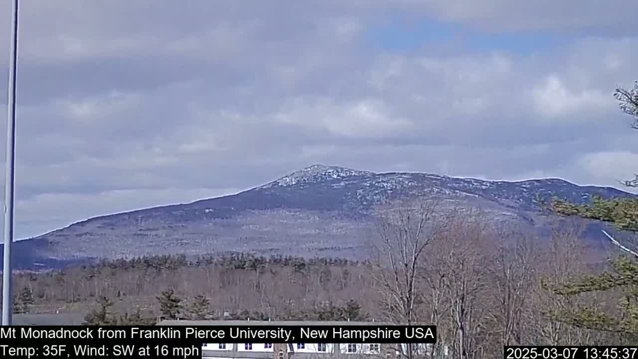 A snow-dusted mountain is visible in the distance under a partly cloudy sky.