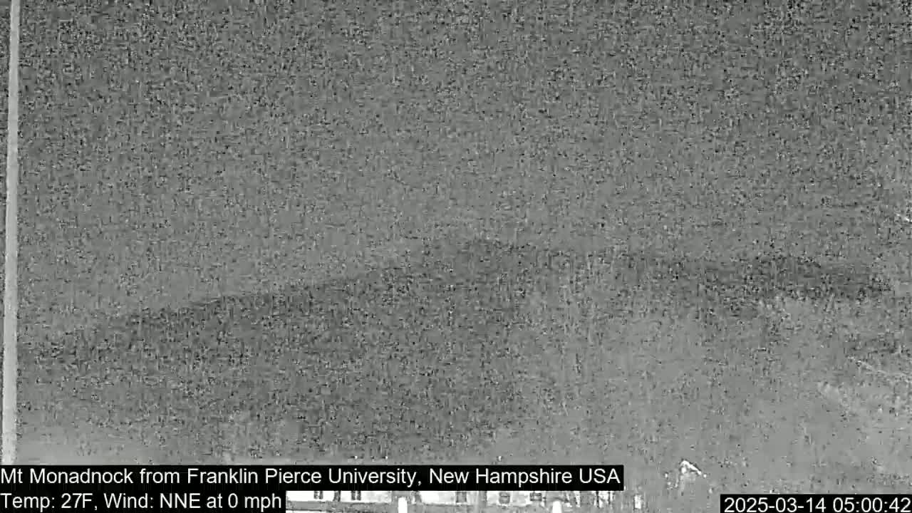 A low-light, grainy image shows a distant, dark mountain under a night sky.