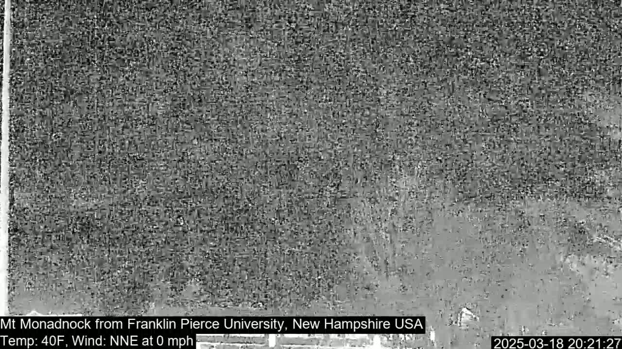 A grainy, low-light image shows a dark, indistinct landscape under a dark sky.
