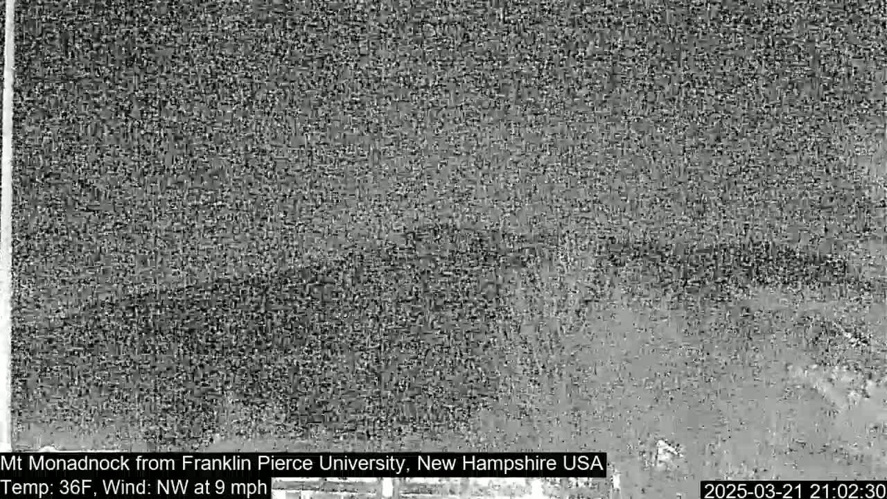 A grainy, low-resolution image shows a dark, blurry landscape under a cloudy sky.