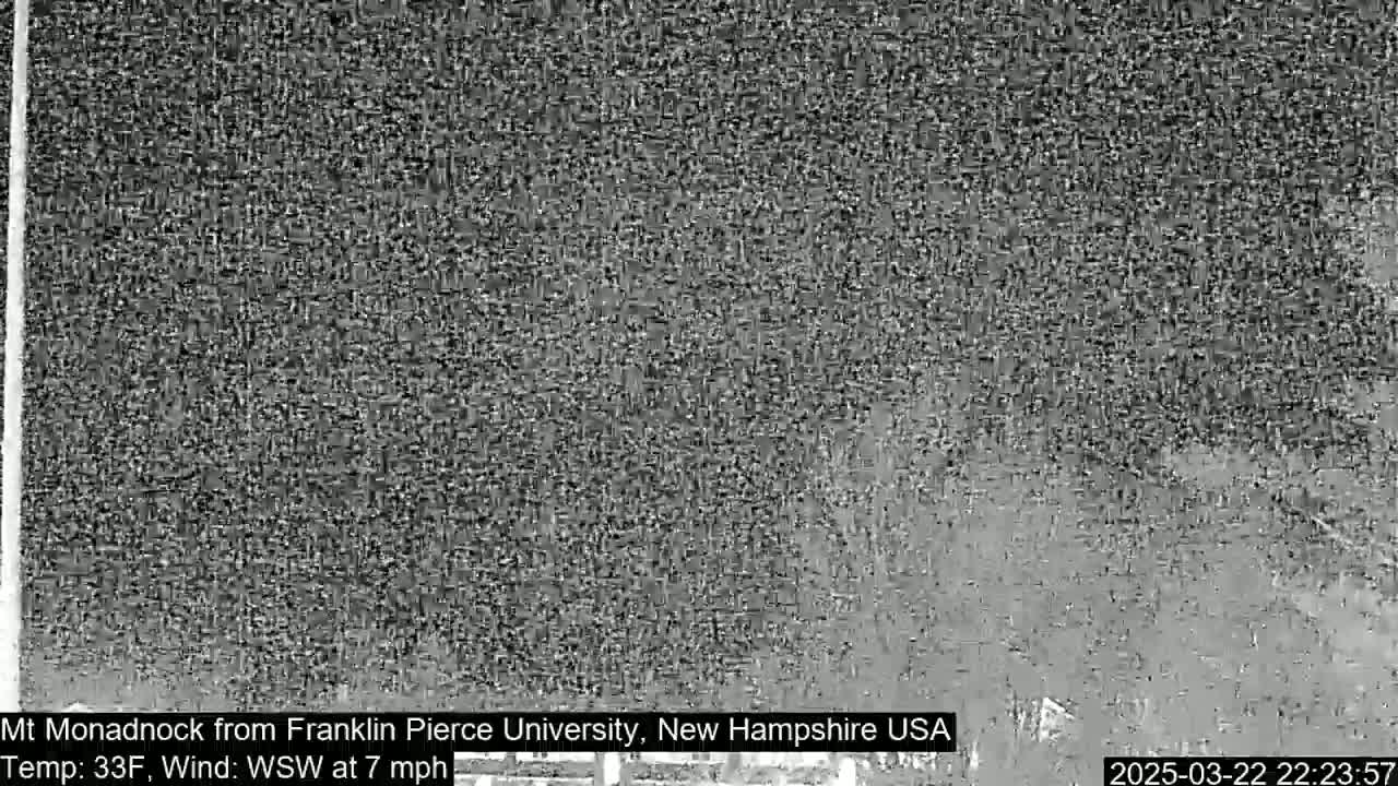 A low-resolution, grayscale image shows a distant, indistinct view of a mountain under a 33°F, overcast sky with a 7 mph wind from the west-southwest.