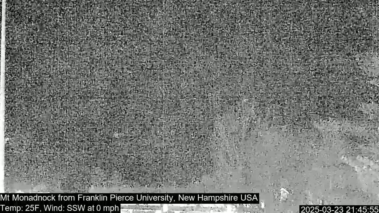 A grainy, low-light image shows a dark, indistinct landscape under calm, cold conditions.