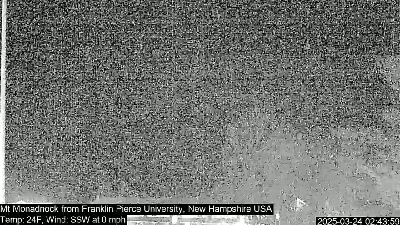 A grainy, low-visibility image shows a dark, possibly snowy landscape at night with calm winds and a temperature of 24 degrees Fahrenheit.