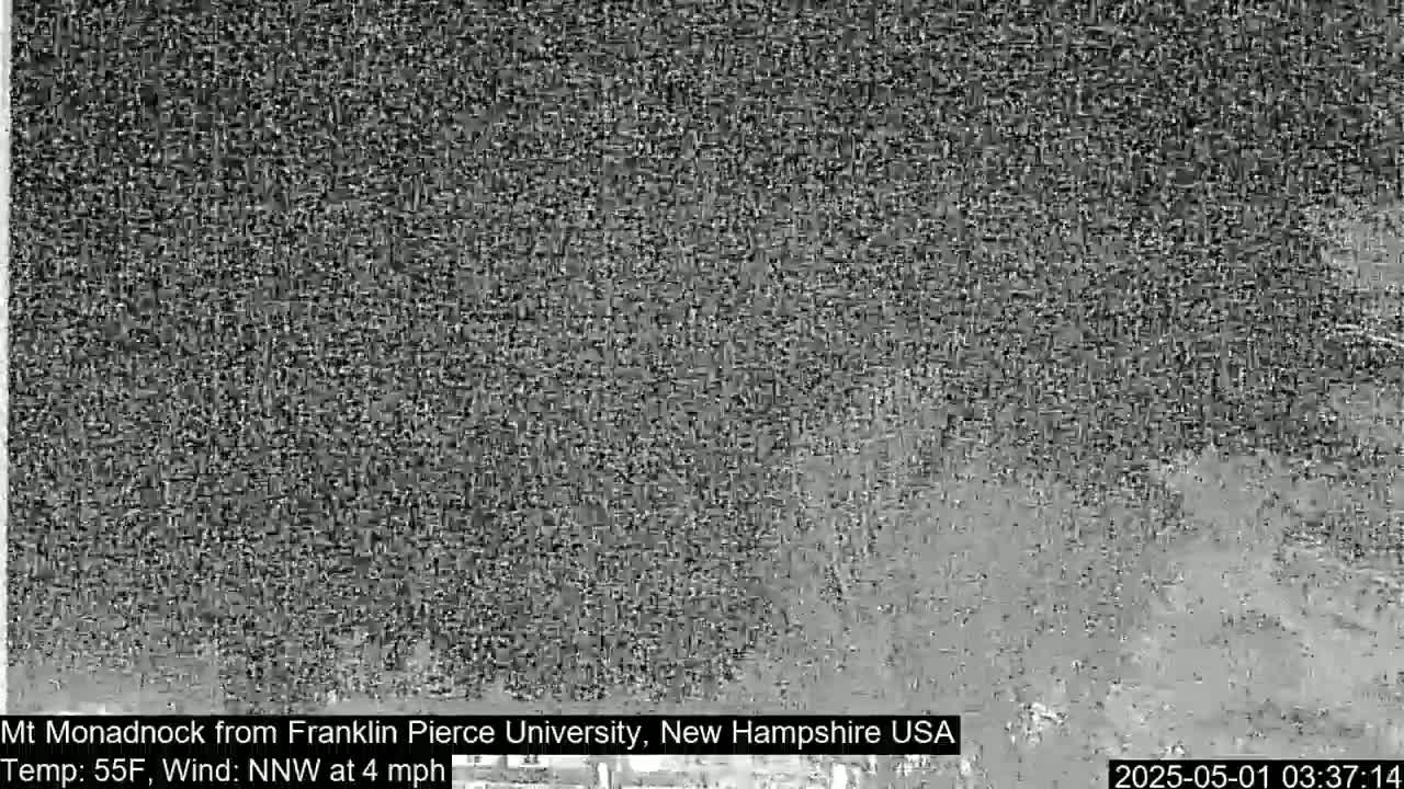 A grainy, black and white image shows a distant, indistinct view of a landscape under overcast conditions.