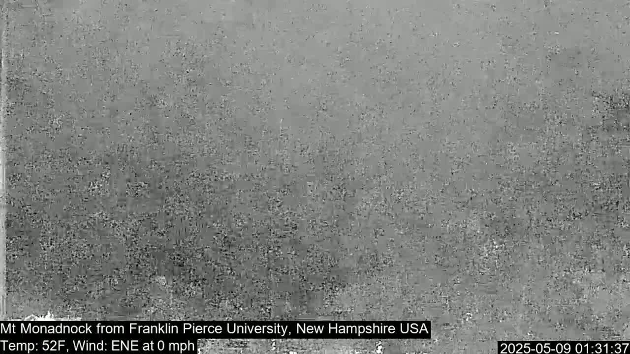 A grainy, low-resolution image shows a mostly indistinct, gray landscape under calm conditions.