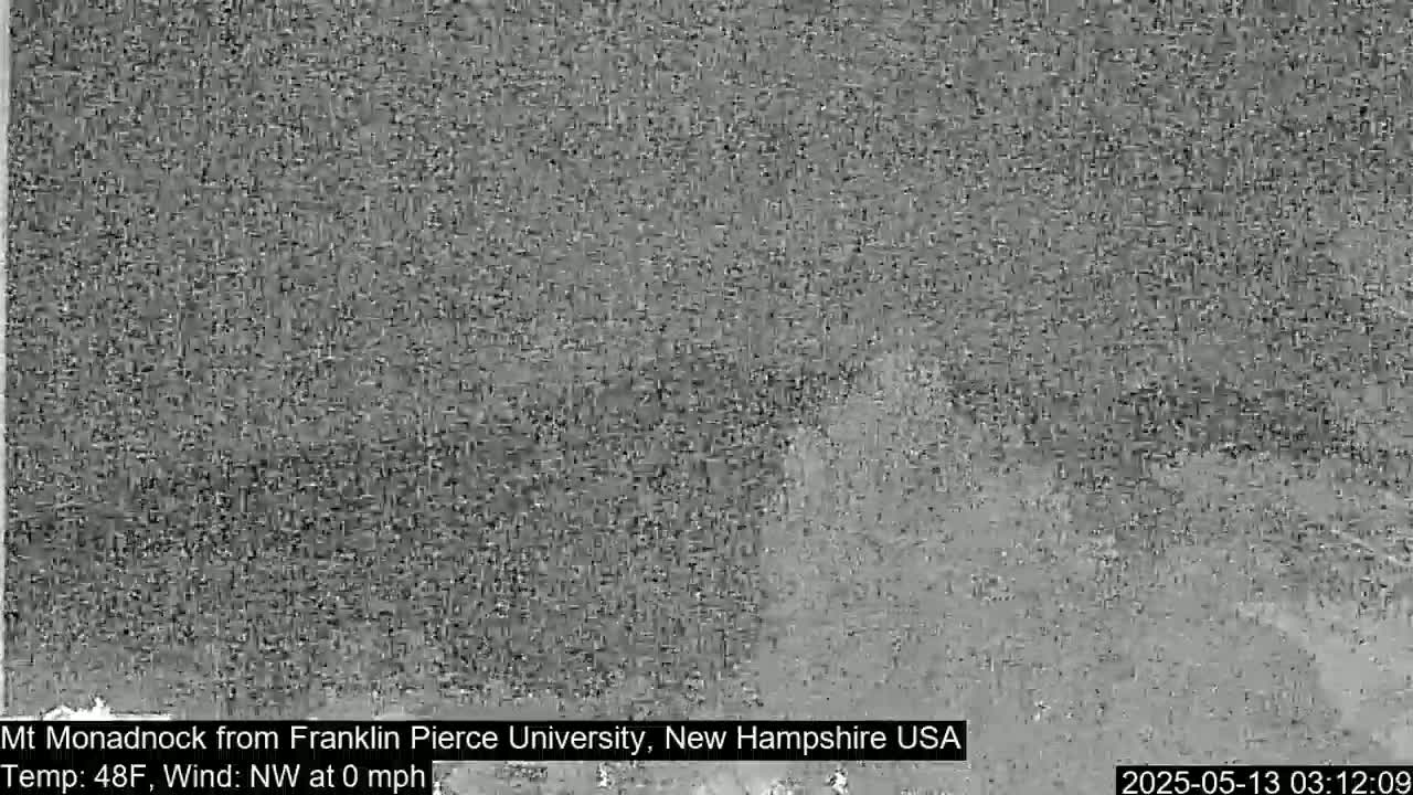 A blurry, grayscale image shows a distant, indistinct view of a mountain under calm, nighttime conditions.